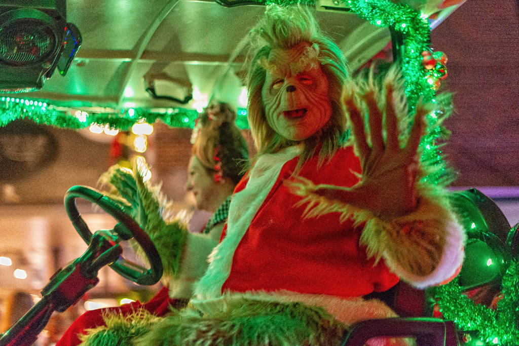 La imagen muestra a una persona disfrazada de Grinch durante un desfile.