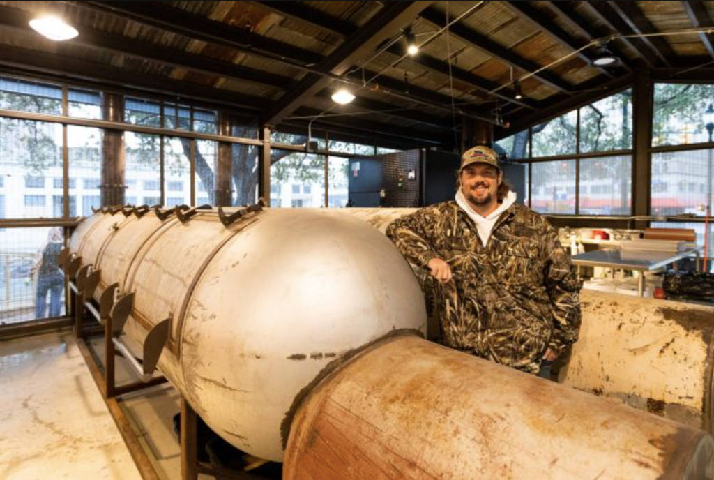 Image shows Pinkerton's Barbecue founder, Grant Pinkerton, posing with a smoker.
