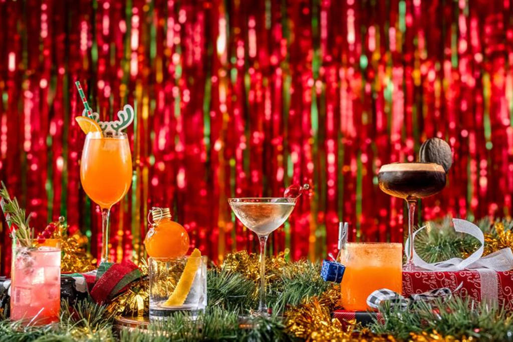La imagen muestra un surtido de cócteles delante de oropeles navideños.