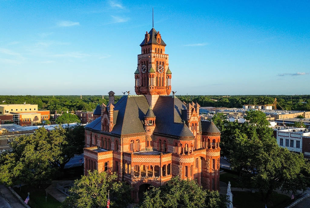 Image shows the Ellis County Courthouse in Waxahachie, Texas surrounded by trees.