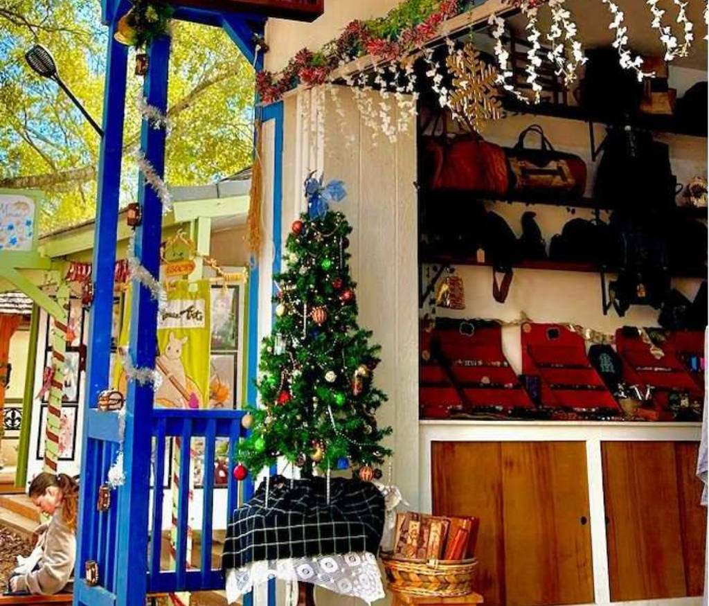 Image shows a decorated stand at the Sherwood Forest Faire with a small Christmas tree in the foreground.