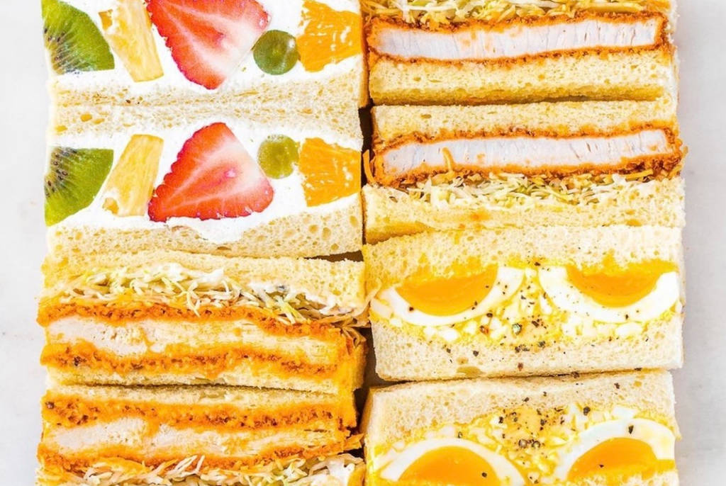 Image shows a variety of Sandoitchi sandwiches stacked on top of each other.