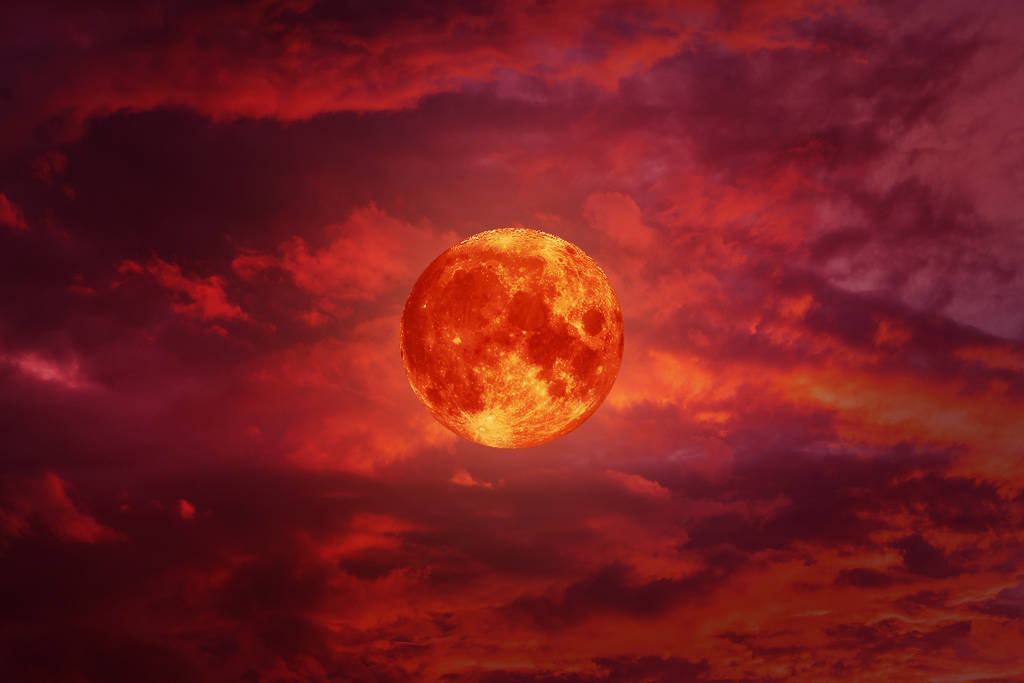 Image shows a blood moon in the sky with a reddish tint.