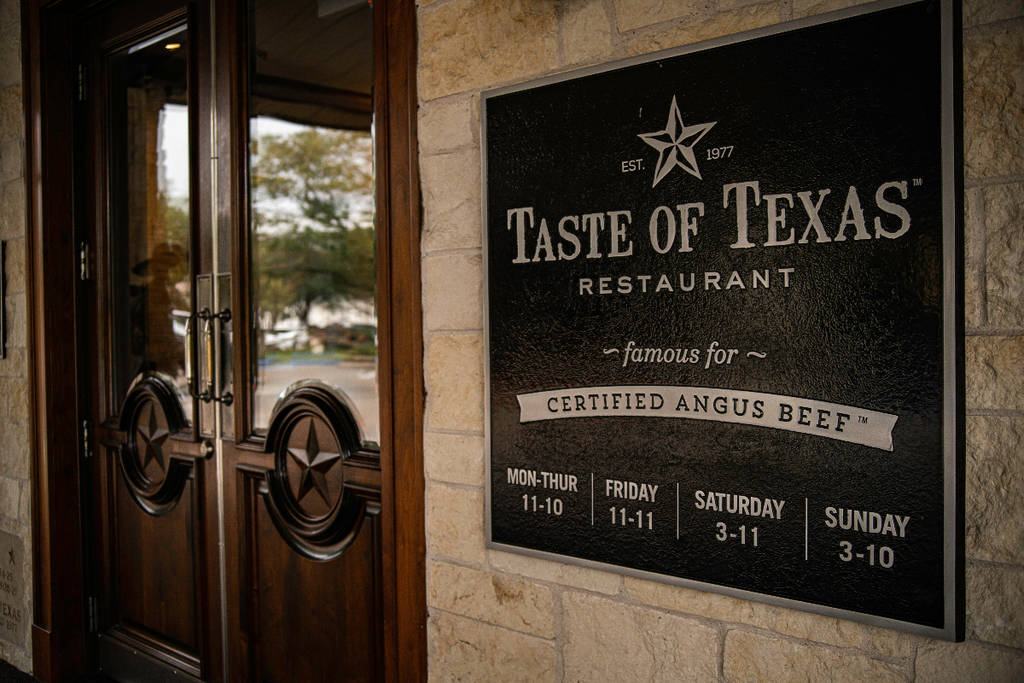 Image shows the entrance of Taste of Texas showing the entrance plaque and doorway.