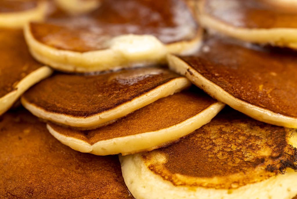 Image shows a stack of pancakes with a slab of butter on top.