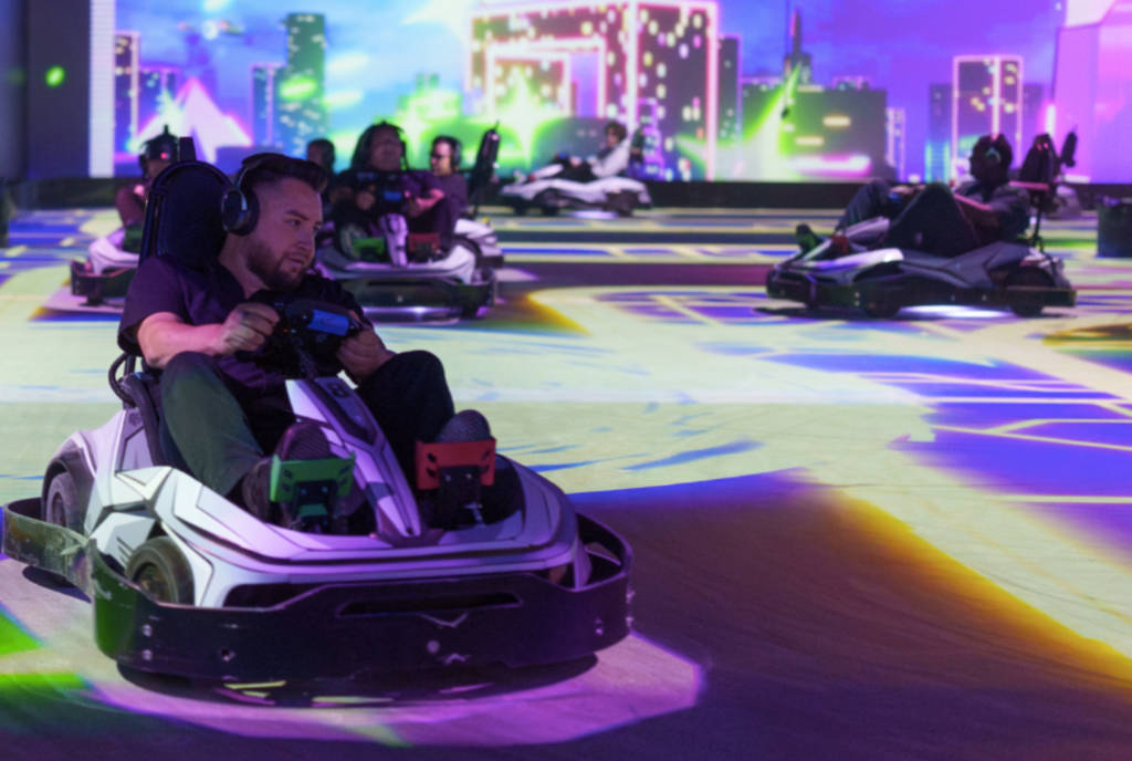 Image shows participants racing Quantum Go-Karts on an AR-infused track at Shenaniganz in Texas.