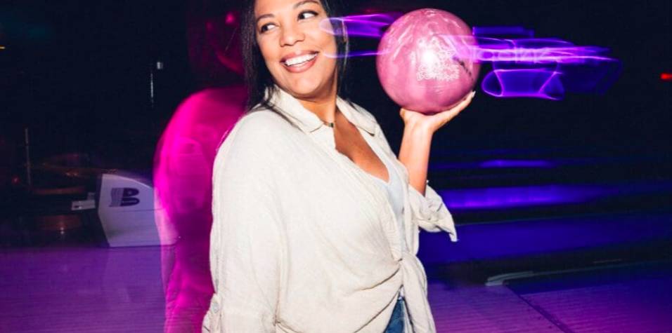 Image shows a woman holding up a bowling ball at Shenaniganz in Texas.