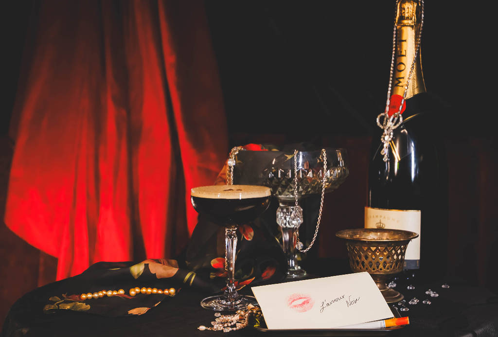 Image shows a display of cocktails and thematic elements for the L'Amour Noir pop-up in Houston.