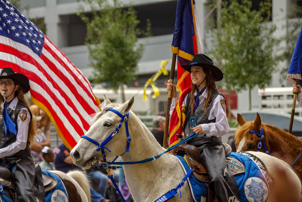 Image shows a woman dressed in Western ware on horseback during the Houston Rodeo Downtown Parade.