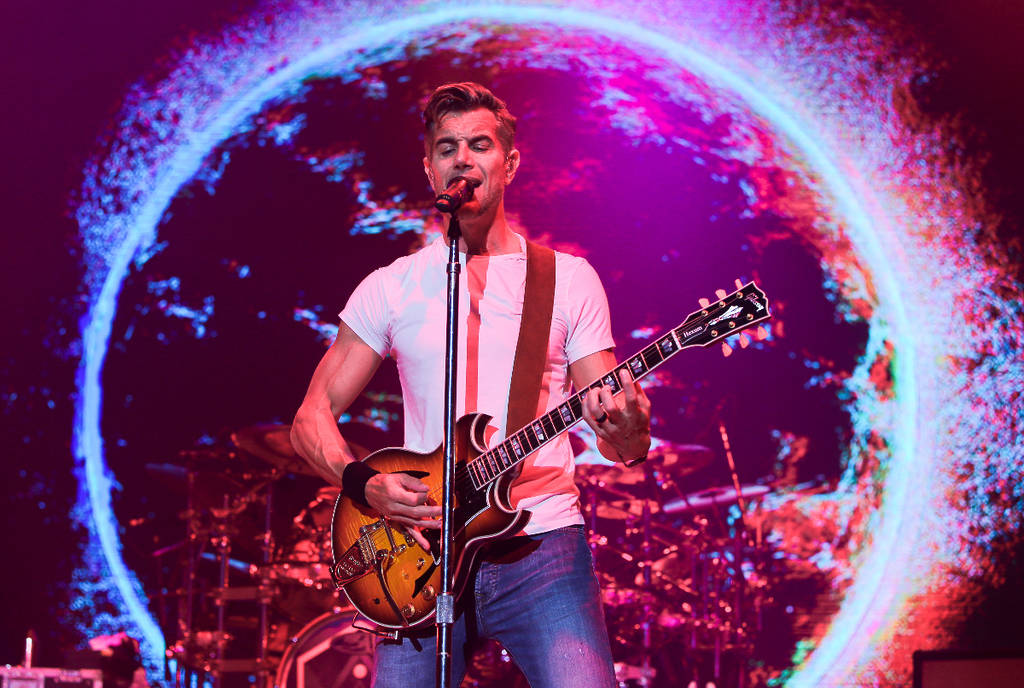 Image shows 311 frontman Nick Hexum playing guitar and singing during a performance.