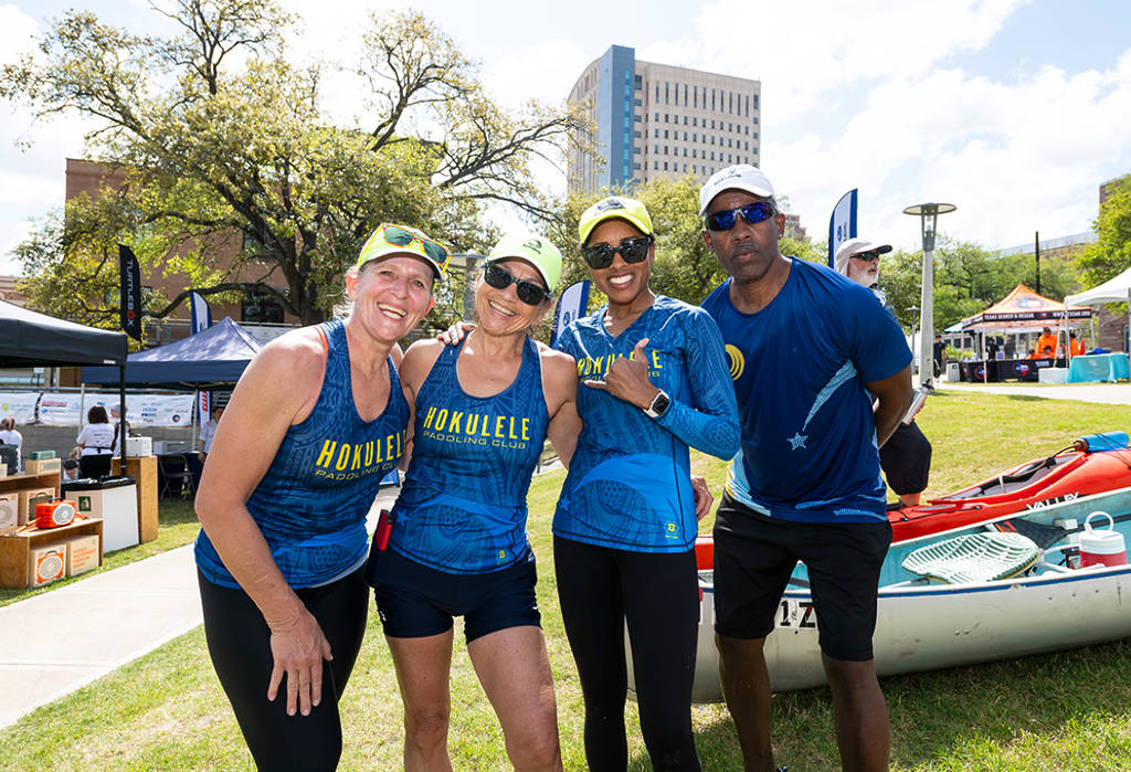 La imagen muestra a un equipo de participantes posando para una foto en honor a la regata de la Buffalo Bayou Partnership en Houston.