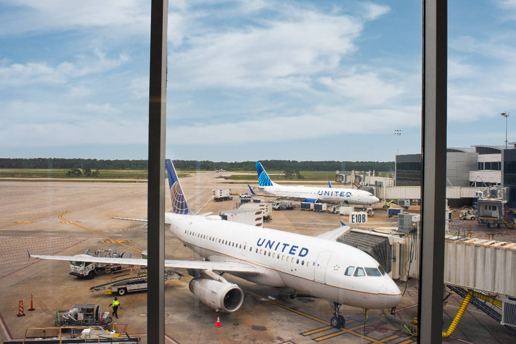 La imagen muestra un avión esperando en su puerta de embarque en un aeropuerto de Houston.
