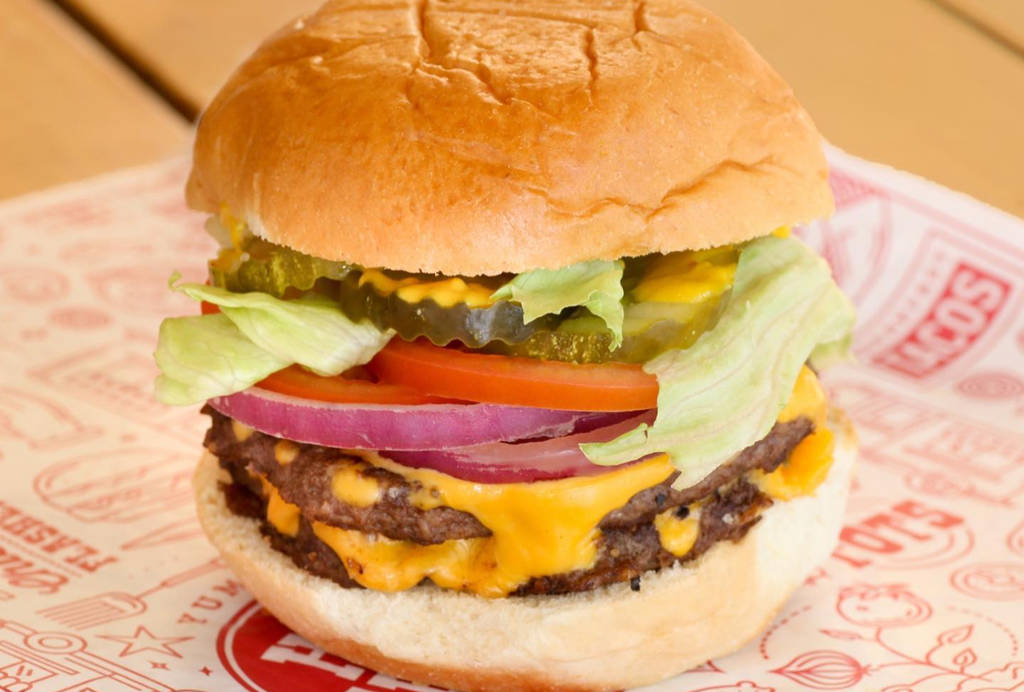 La imagen muestra una hamburguesa con queso servida en Hat Creek Burger Company.