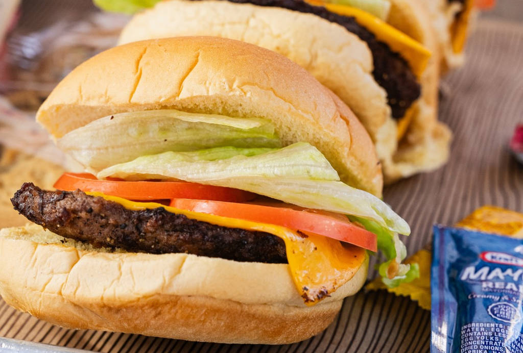 La imagen muestra unas cuantas hamburguesas con queso expuestas en Hat Creek Burger Company.