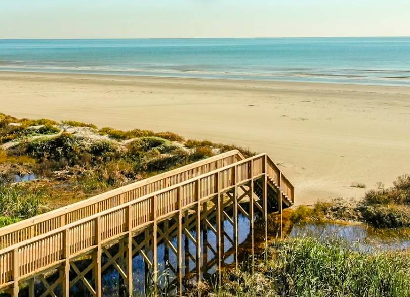 La imagen muestra un paseo marítimo que conduce a la zona de playa de Jamaica Beach en Galveston, Texas