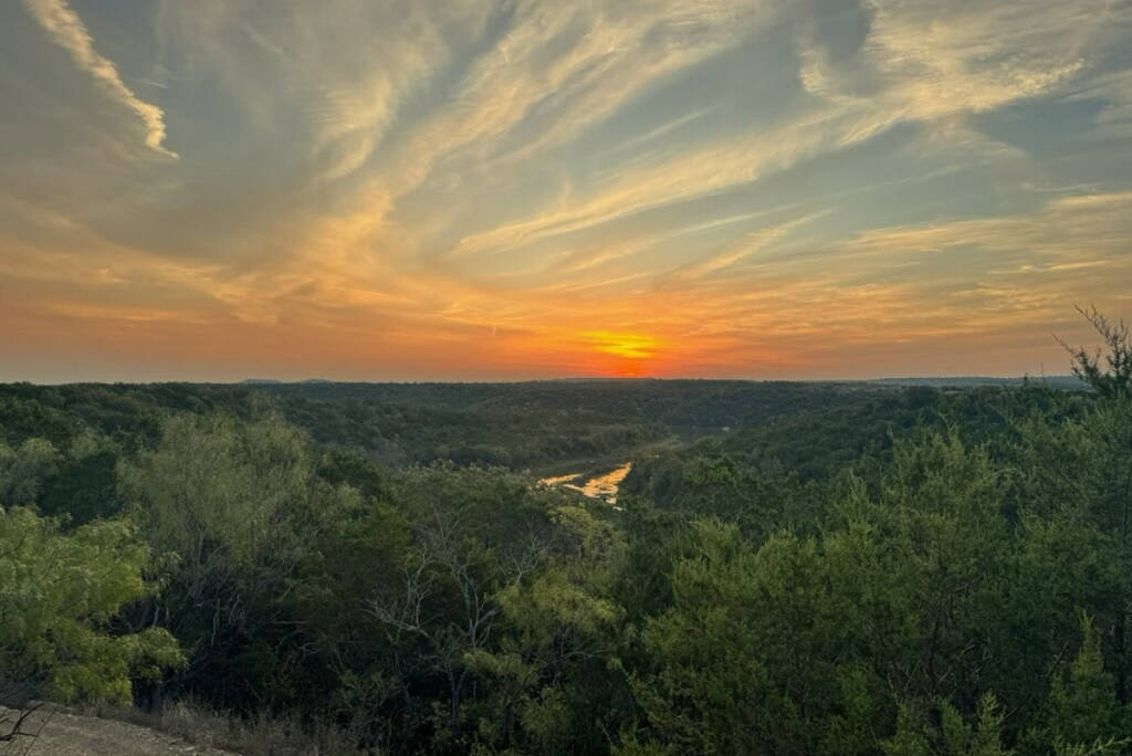 La imagen muestra una foto del paisaje al atardecer en el Parque Estatal de las Montañas Palo Pinto, en Texas. 