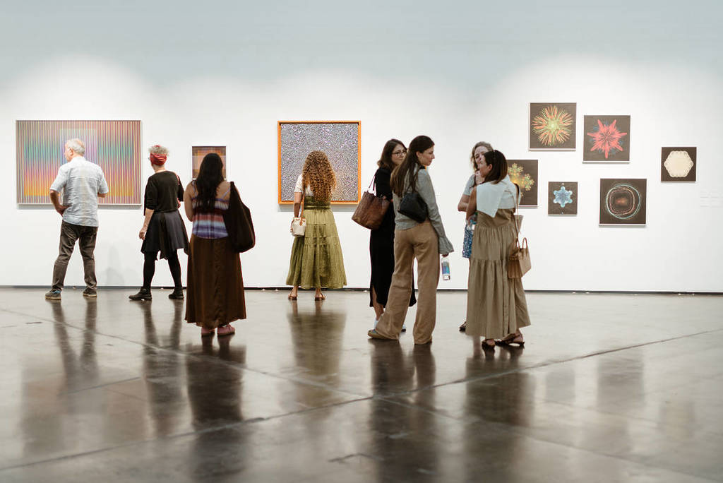 Image shows the inside of a gallery as visitors look on during Untitled Art in Houston.