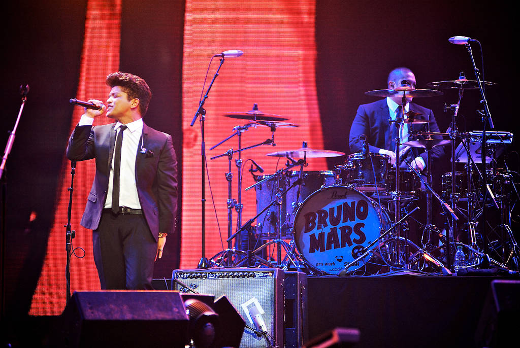 Image shows Bruno Mars performing on stage.