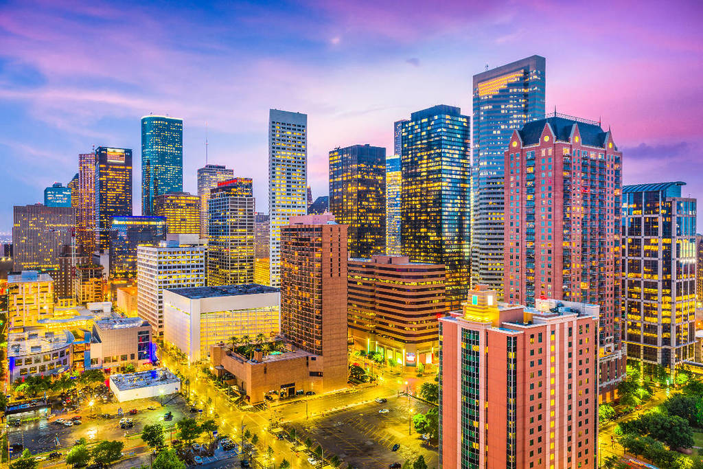 La imagen muestra el perfil urbano de Houston iluminado al atardecer.