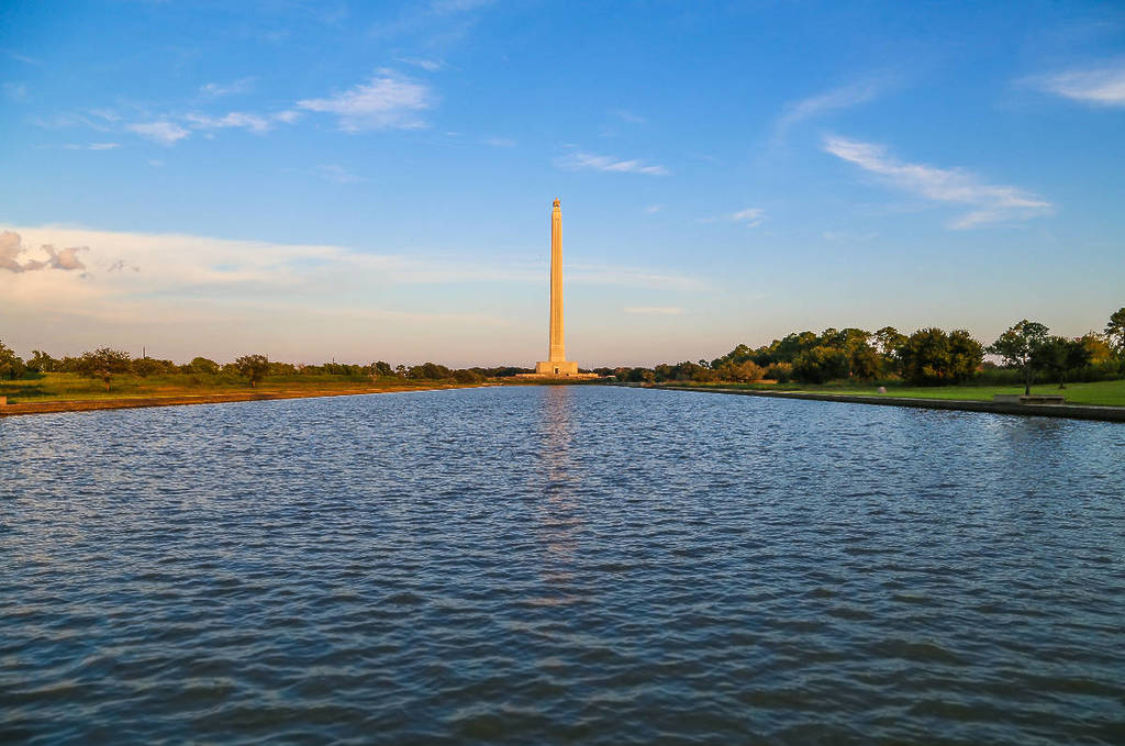 Image shows the San Jacinto Monument from across a body of water. 