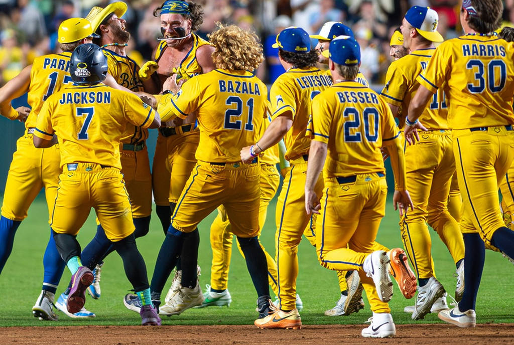 La imagen muestra a las jugadoras de las Savannah Banana celebrando en el campo de béisbol.
