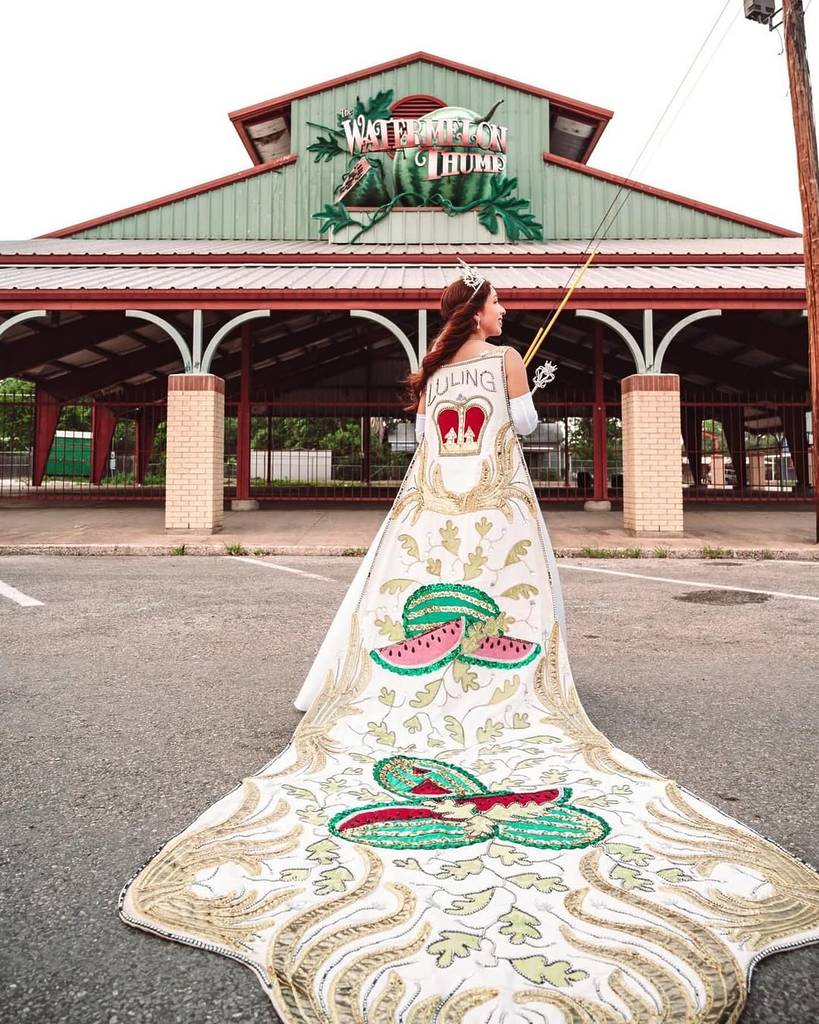 Image shows the Watermelon Queen posing in front of a building in Luling, Texas. 