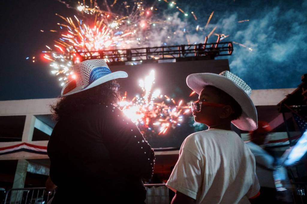 Image shows a mother and son looking on at a fireworks display at Liberty Fest in Houston. 