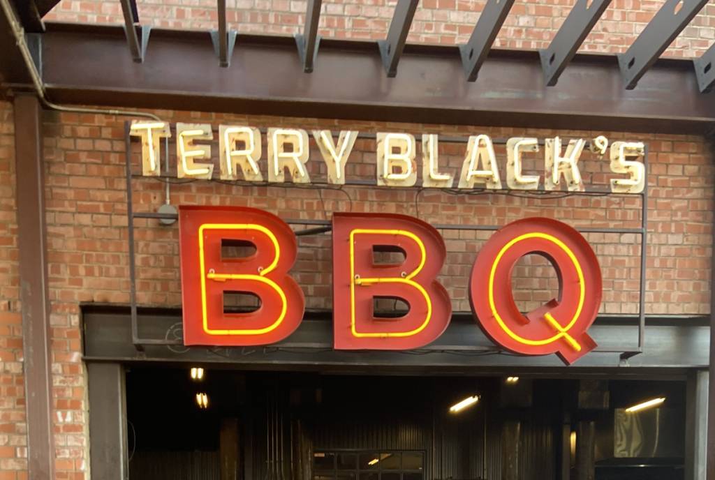 La imagen muestra el letrero y la entrada de Terry Black’s BBQ