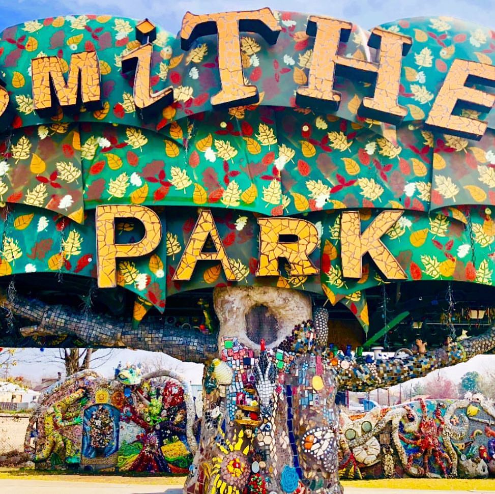 La imagen muestra una instalación de mosaicos en forma de árbol con el letrero «Smither Park». 