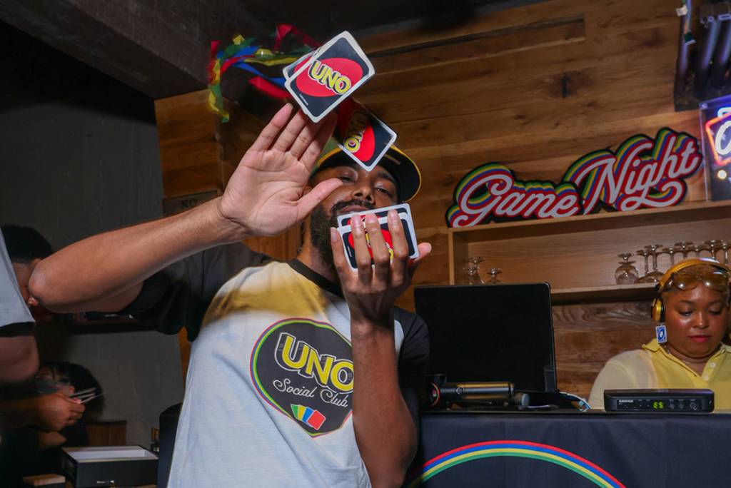 Image shows a man making it rain with UNO cards at a UNO Social Club pop-up.