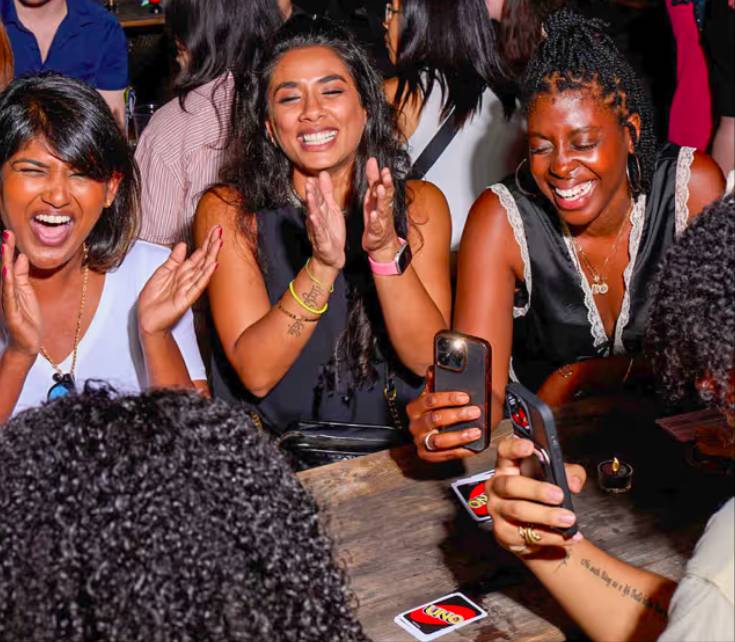Image shows a lively atmosphere and group of people at a UNO Social Club. 