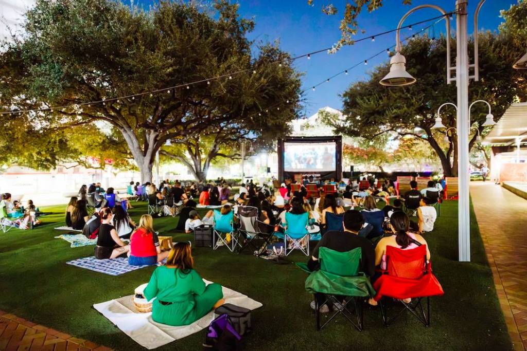 La imagen muestra a gente viendo una película en el Market Square Park de Houston. 