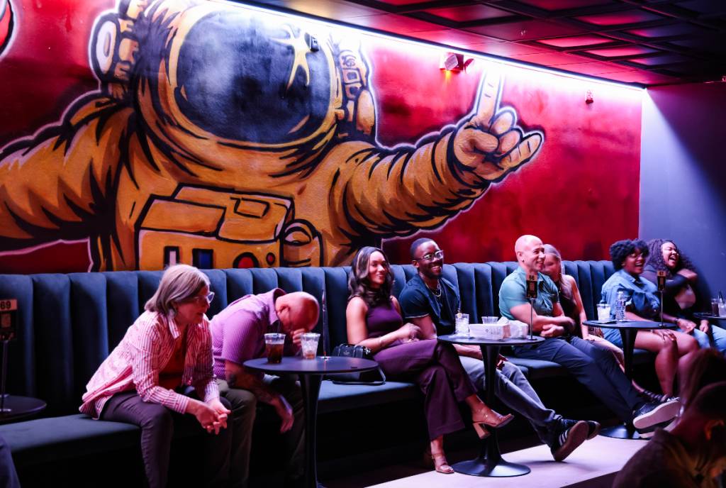 Image shows the astronaut mural at Riot Comedy Club in Houston with visitors hanging out.