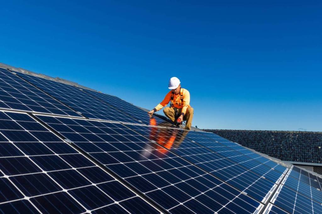 La imagen muestra a un hombre instalando paneles solares. 