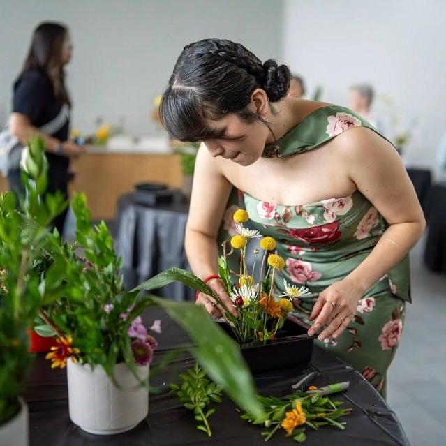 Image shows a woman managing a floral arrangement. 