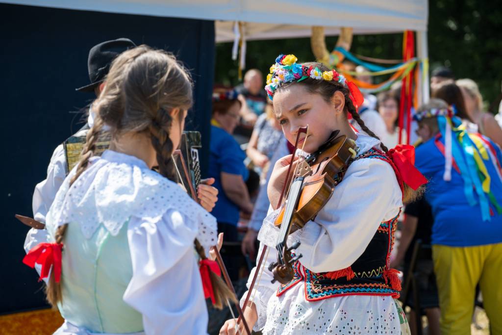 Image shows two girls in traditional Polish dress playing instruments.