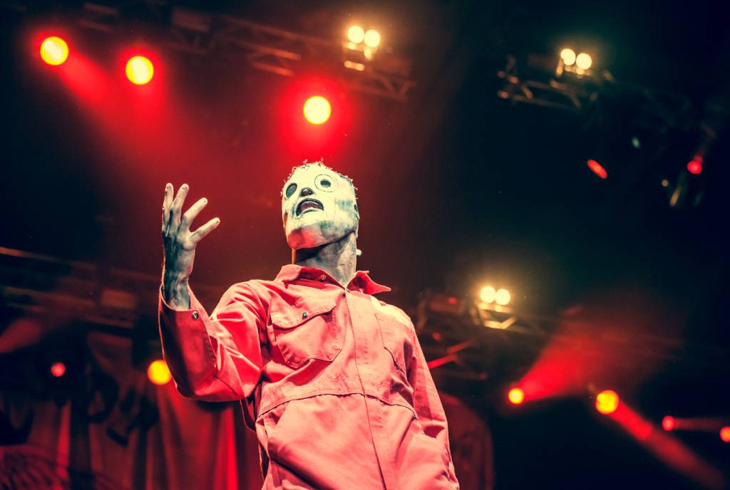 La imagen muestra a Corey Taylor, de Slipknot, con máscara y mono, actuando en el escenario.