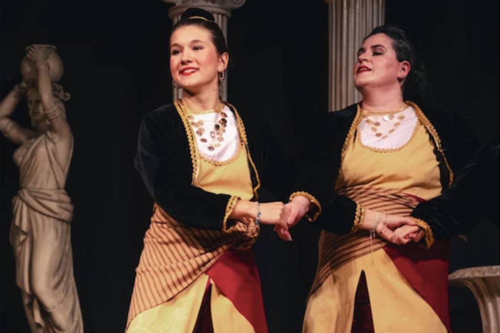 Image shows two dancers in traditional Greek dress performing at the Original Greek Festival in Houston. 