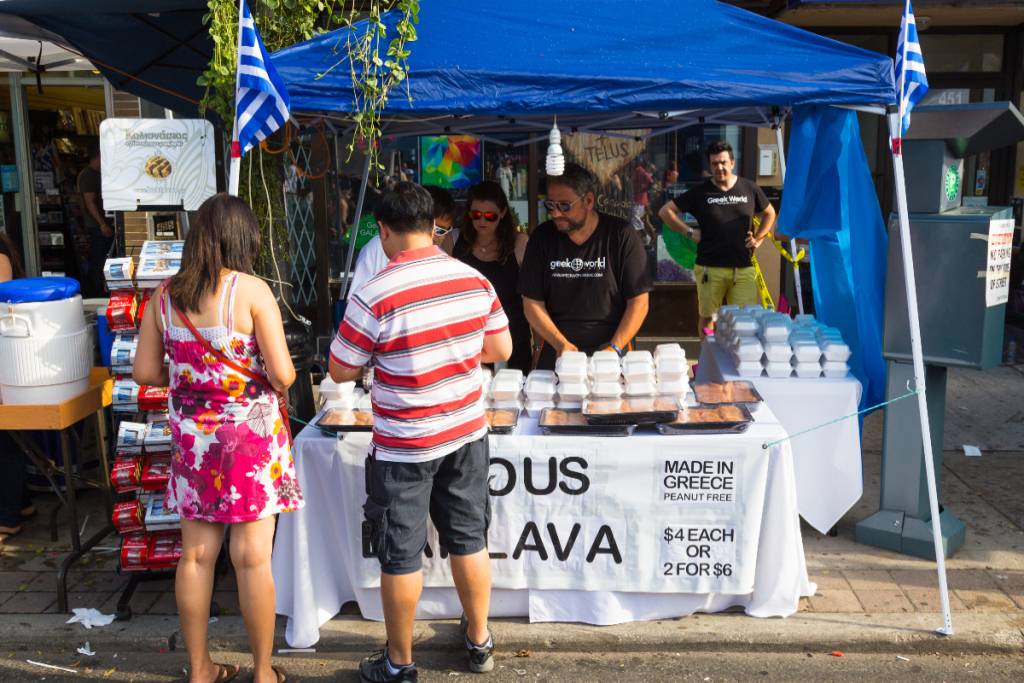 Image shows festival-goers patronizing a Greek food stand.