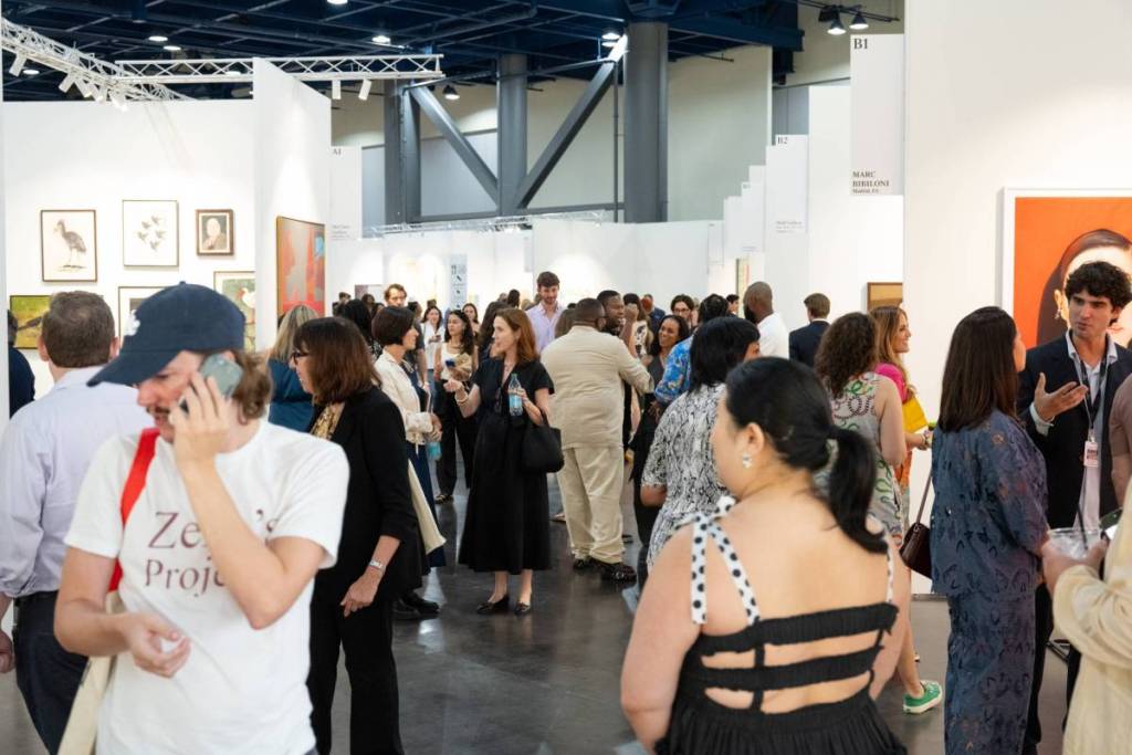 La imagen muestra a un grupo de personas en una galería de arte durante la feria Untitled Art de Houston.