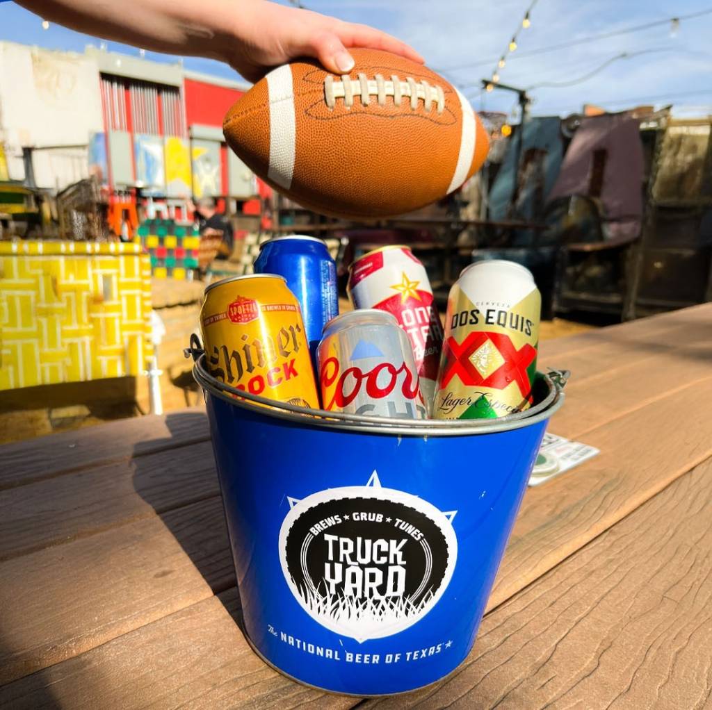 La imagen muestra a una persona sosteniendo un balón de fútbol americano sobre un cubo de cerveza.
