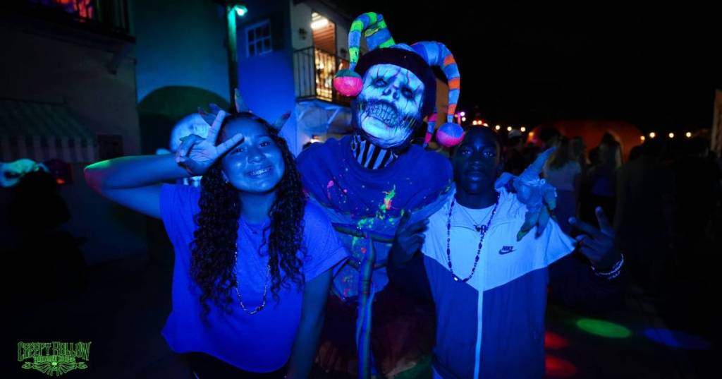 La imagen muestra a dos personas posando con una espeluznante figura de Halloween. 