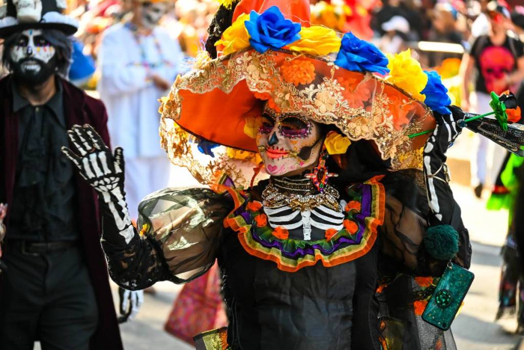 La imagen muestra un desfile del Día de los Muertos.