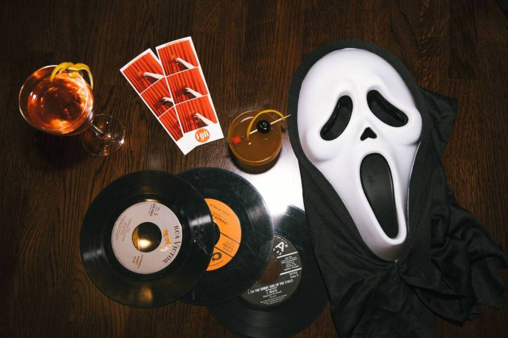 Image shows a ghostface mask, records, cocktails, and photos.