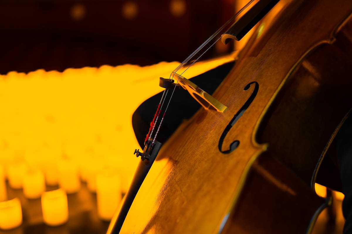 Primer plano de un violonchelo sobre un escenario cubierto de velas durante un concierto Candlelight.