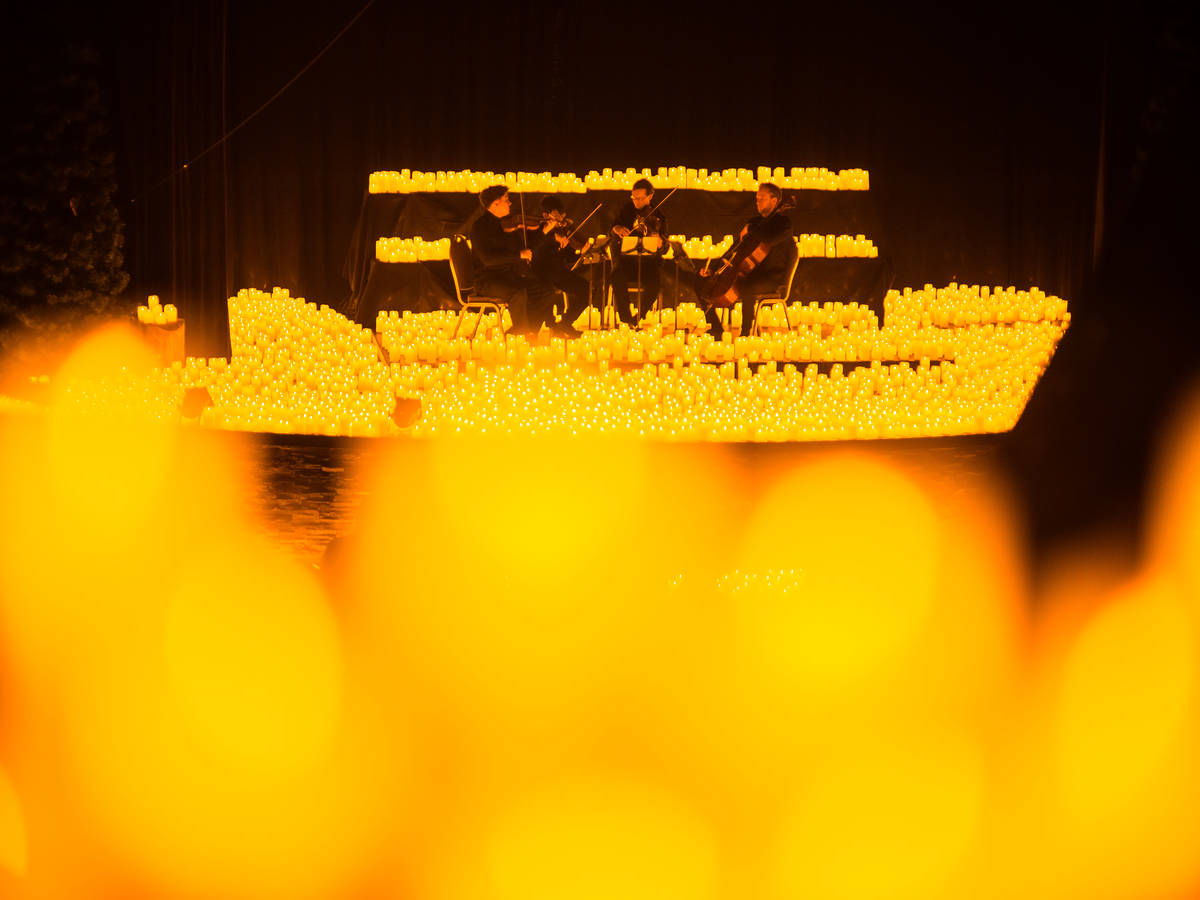 Un cuarteto de cuerda toca sobre un escenario cubierto de velas durante un concierto Candlelight.