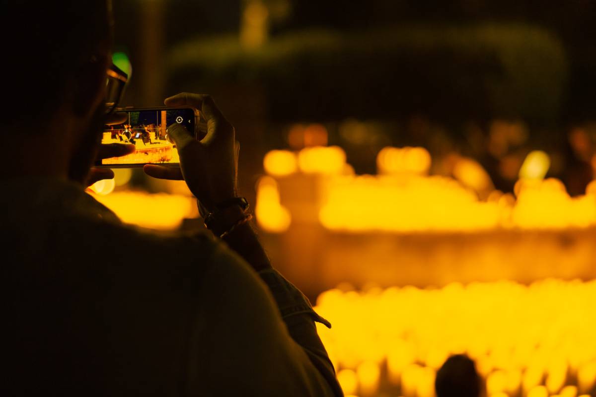 Una espectadora hace fotos a un escenario cubierto de velas durante un concierto Candlelight.