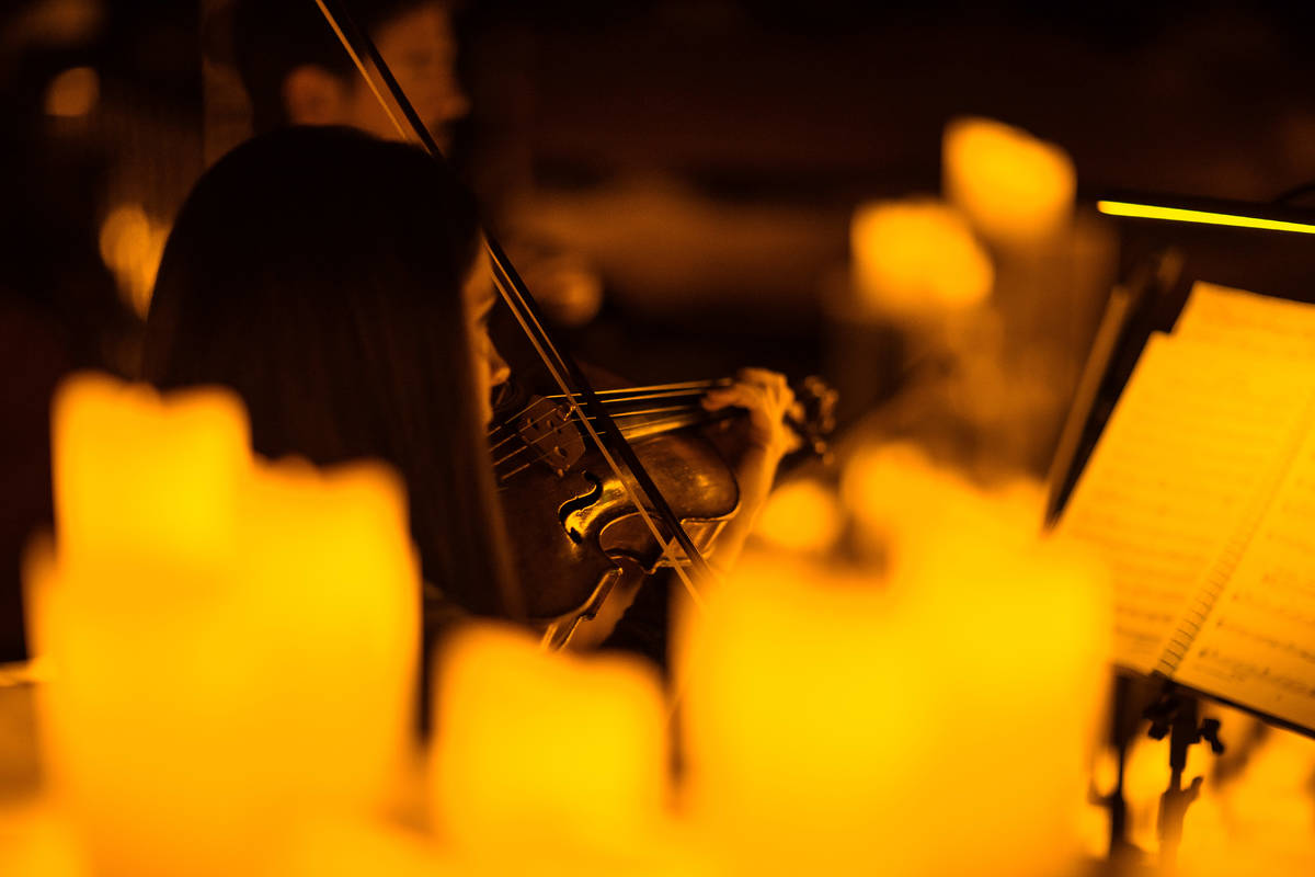 Primer plano de una violinista rodeada de cálidas velas durante un concierto Candlelight.