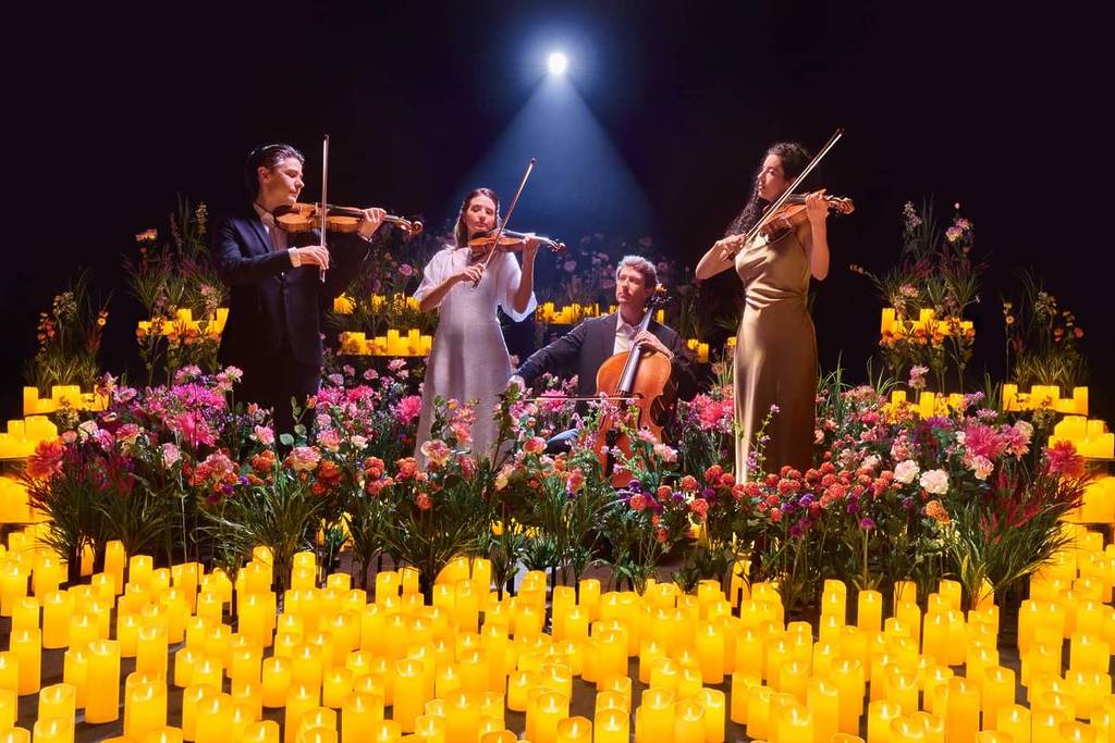 string quartet performs surrounded by candles and flowers