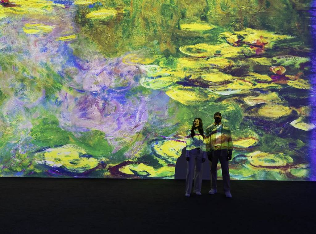 two people admire a projection of Monet's waterlilies at the immersive Monet experience
